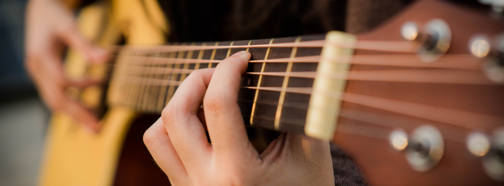 Close-up van iemand die akoestische gitaar speelt.