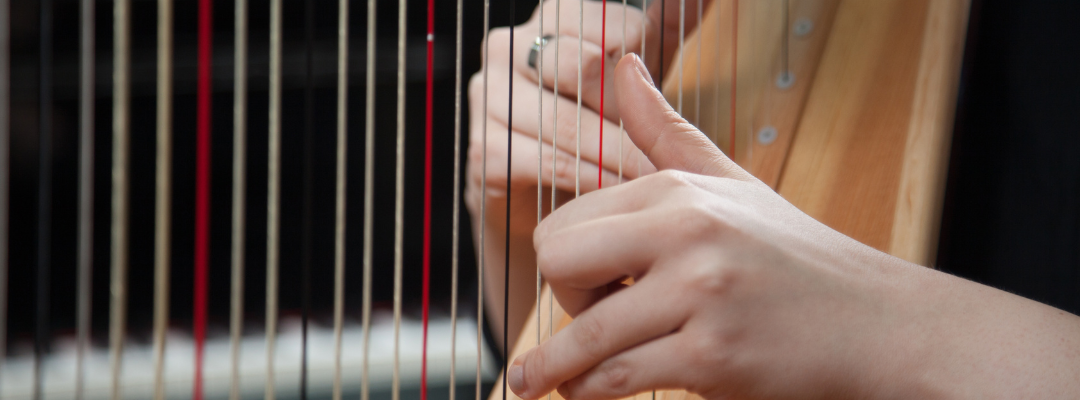 Close-up van iemand die harp speelt.