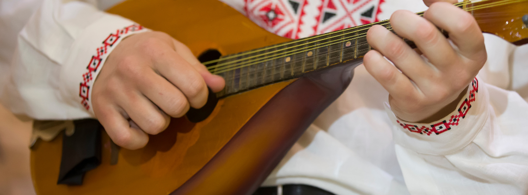 Close-up van iemand die de mandoline bespeelt. 