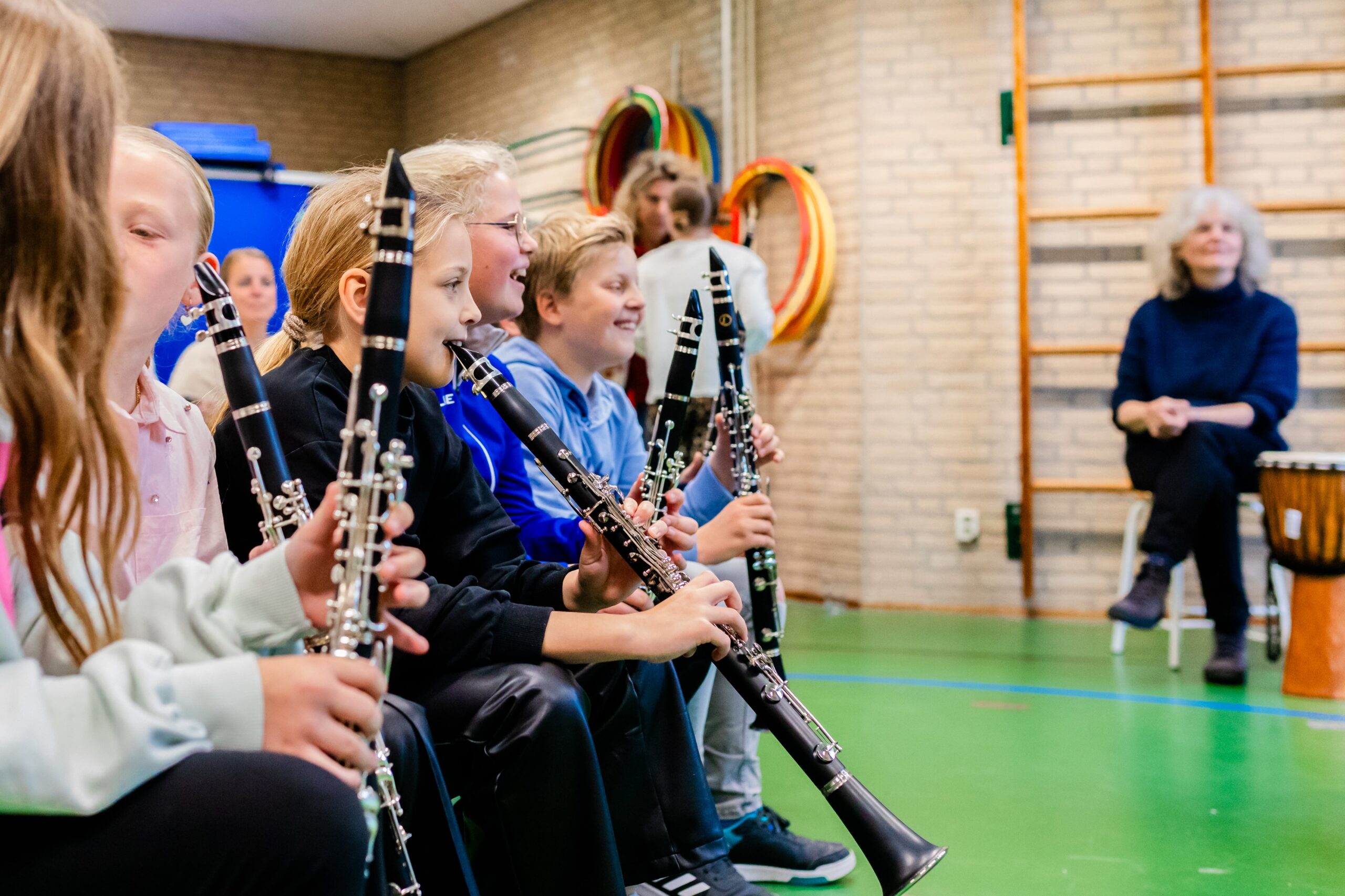 Kinderen krijgen muziekles in de gymzaal op school van een Planck muziekdocent.