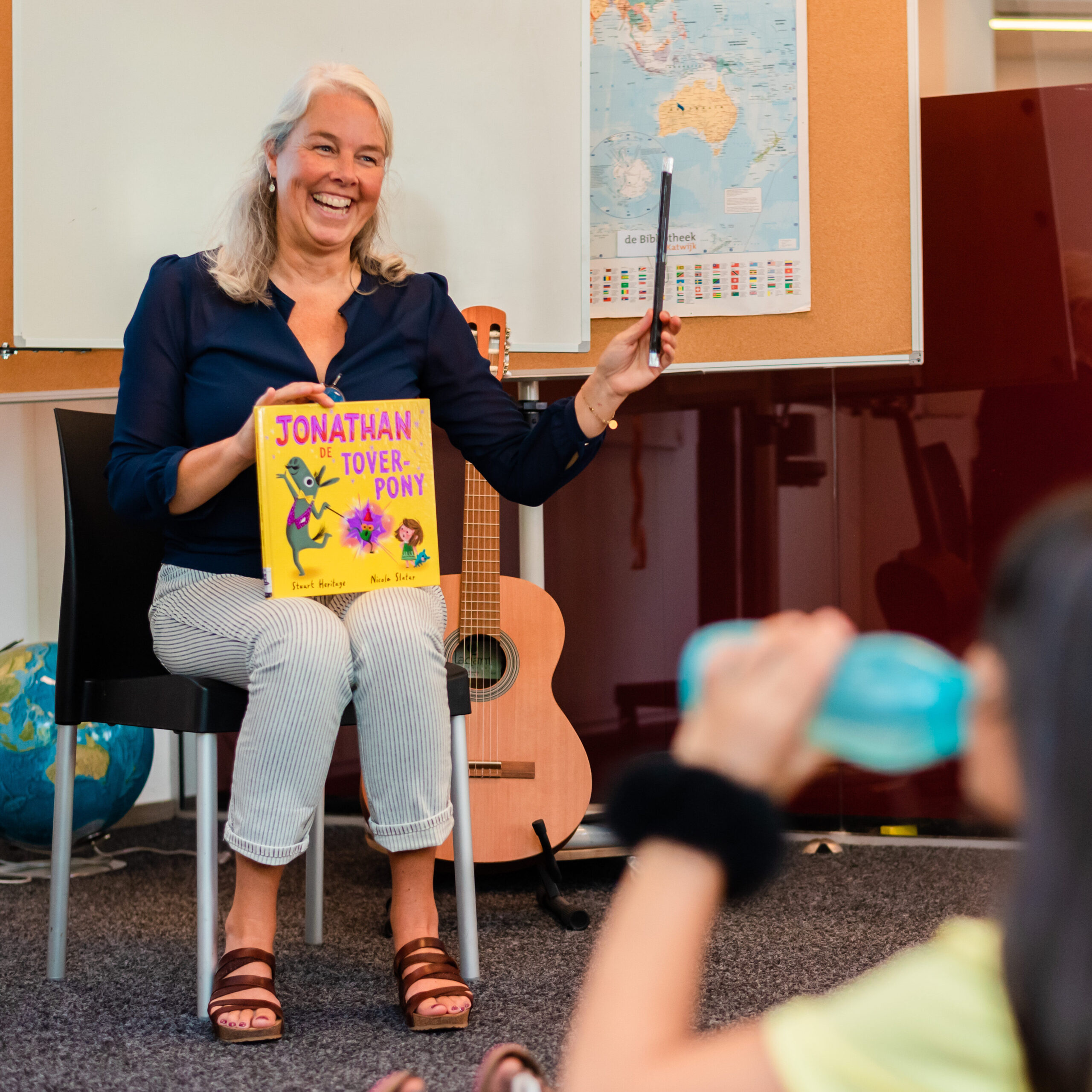 Een planck medewerker leest een kinderboek voor aan kinderen in het digiTaalhuis