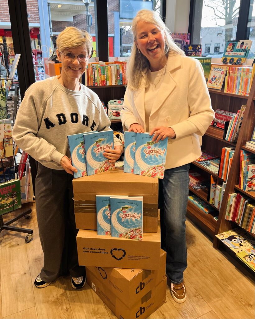 Marianne Hoek van Readshop Rijnsburg en Petra Jansen van Planck poseren bij stapel gedoneerde boeken