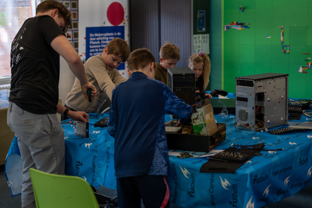 Kinderen halen computers uit elkaar tijdens de Tech Week bij Planck.